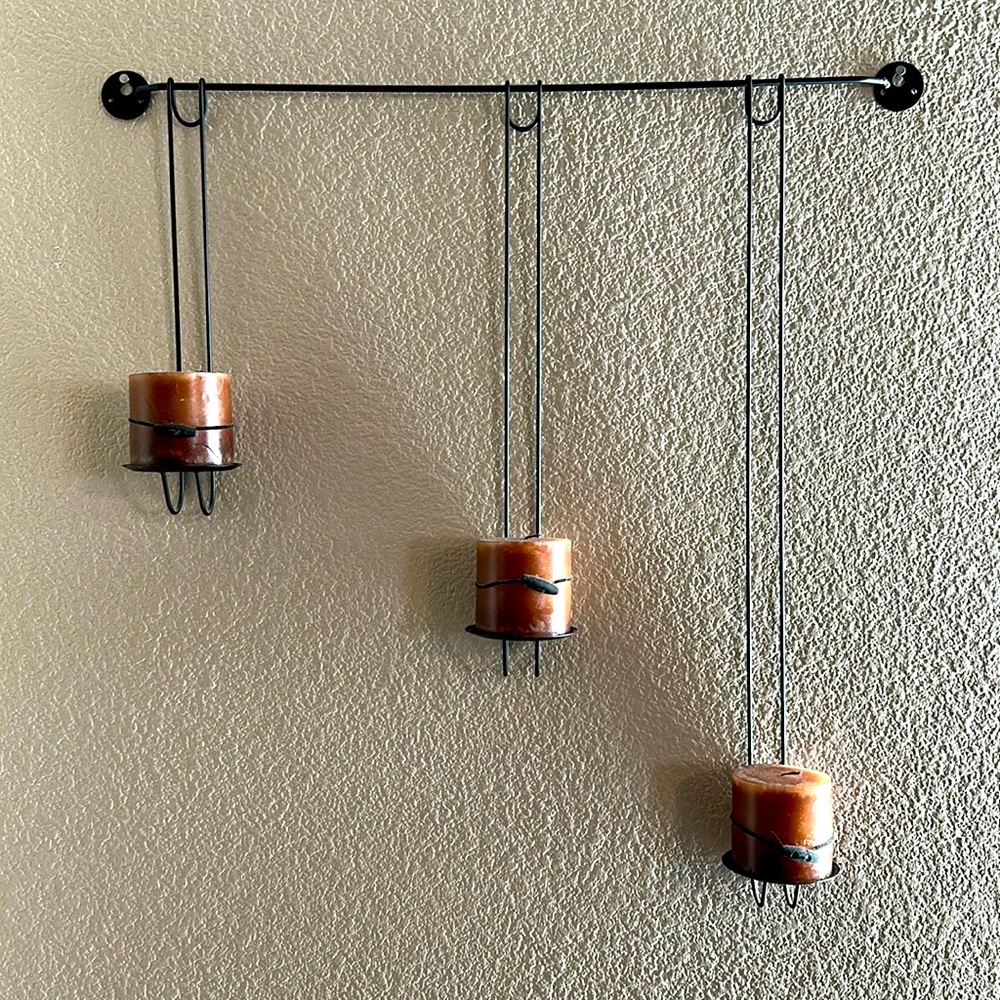 Wall mounted candle holder with adjustable hangers.